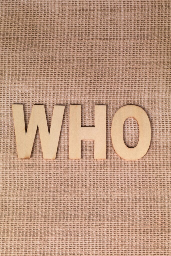 Wooden letters spelling WHO on a burlap fabric background.